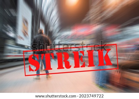 Man waiting for the train on a platform in the big city railway station and banner with German text Streik (meaning strike), blurred crowd background with zoom effect, copy space