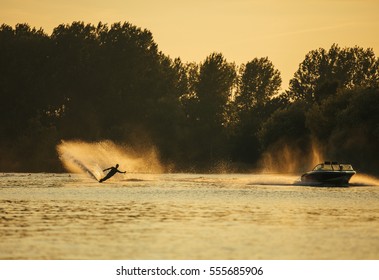 Man wakeboarding on lake behind boat at sunset. Water skiing on lake. - Powered by Shutterstock