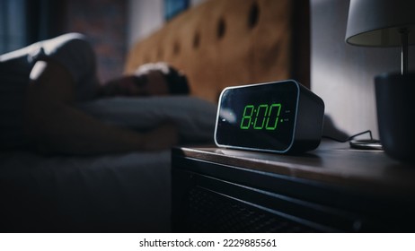 Man Wakes Up and Turns off Alarm Clock. Early Rising Productive Man Ready Start a Day of New Business Opportunities. Focus on the Clock Showing Eight O'Clock on Bedside Nightstand bedroom Apartment