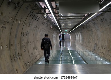 Man walk at underground tunnel.Transport walkway by Tunnel Boring Machine for infrastructure subway with raw concrete segments wall. Light at the end of the tunnel.