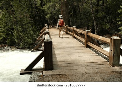 Man Walking Across Bridge over a River