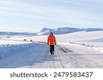A man walking along a frozen road in the cold winter of Iceland