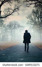 The man is walking along the road in the fog - Shutterstock ID 1049113271