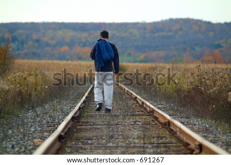 A man walking along train tracks
