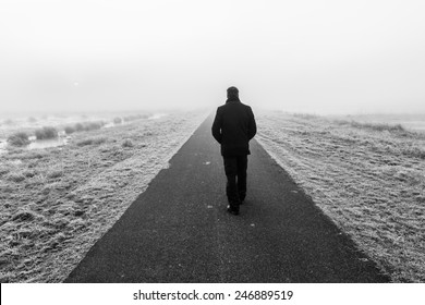 Mann, der auf einer leeren trostlosen Straße weggeht