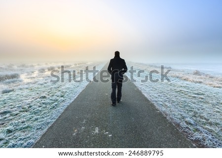 Man walking away on an empty desolate raod
