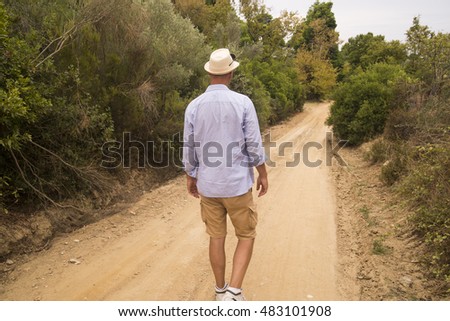 Man walking away on an empty desolate raod