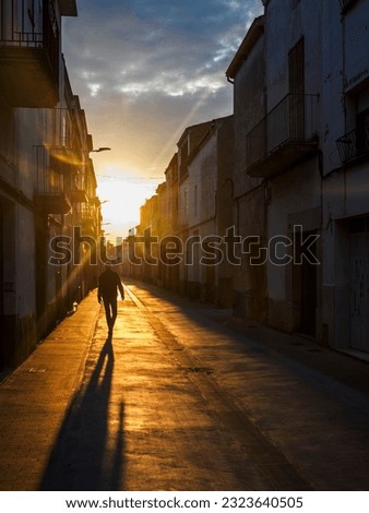 a man walking backwards in a village street at sunset, Catalonia, Spain.