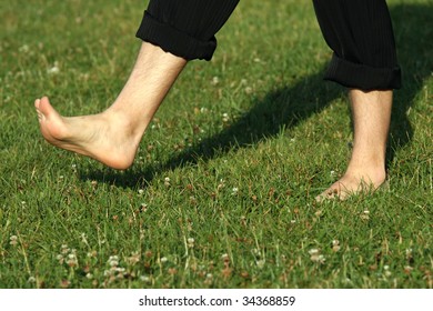 Man Walking Barefoot On A Grass