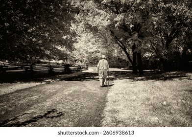 Man walking with cane down a path in period costume for the year 1863