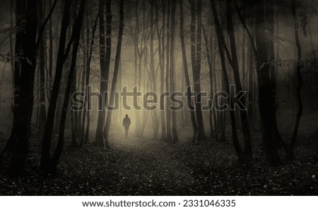 man walking in dark scary forest at night