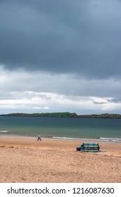 Man Walking And Dark Stormy Clouds At Whiterocks Beach, Portrush, Northern Ireland