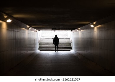 Man walking in dark underground tunnel. Stranger anonymous person. Unknown person in subway. Horror and thriller concept. Light at end of tunnel. - Shutterstock ID 2161821527