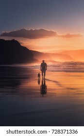 Man Walking The Dog On Beach At Sunset