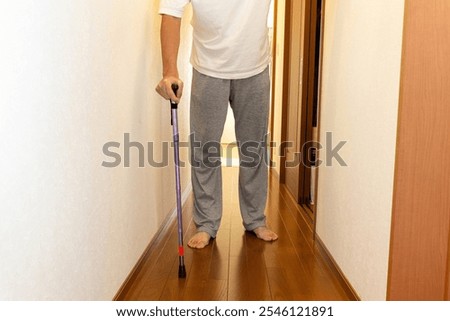 A man walking down a corridor with a cane