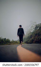 A Man Is Walking Down A Montain Road