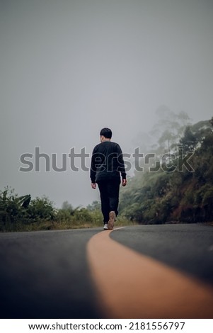 a man is walking down a montain road