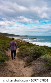 Man walking down path by ocean