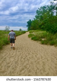man walking down path of sand