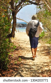 A man walking down a path towards the beach