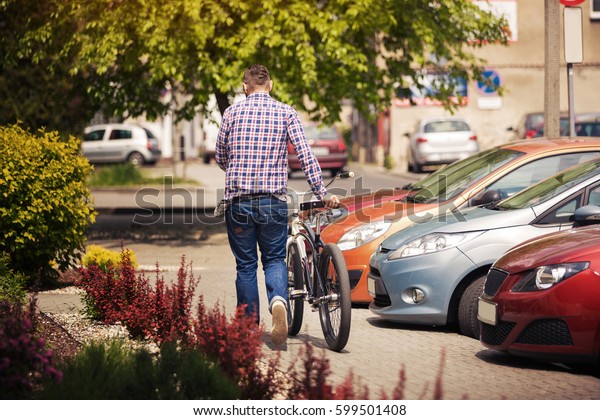 Man walking down the\
street with bicycle