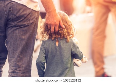 A man is walking down the street with a little girl on a sunny day