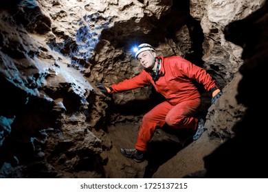 Man walking and exploring dark cave with light headlamp underground. - Powered by Shutterstock