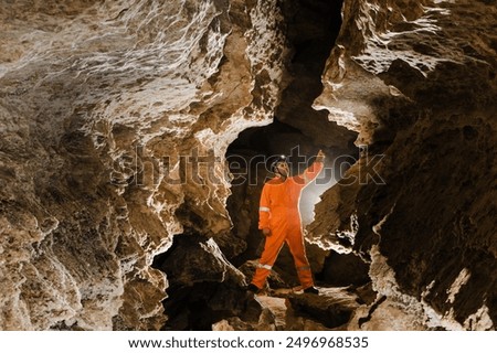 Man walking and exploring dark cave with light headlamp underground.