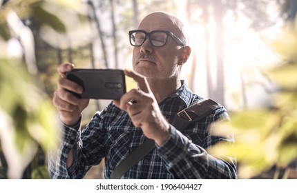 Man walking in the forest and taking pictures using his smartphone - Powered by Shutterstock