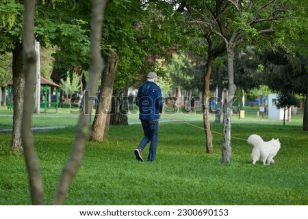 A man is walking his dog in the park.