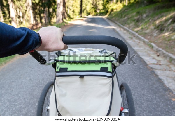 Man walking and jogging outdoors with child\
jogging stroller