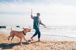 Man Walking With Labrador Dog On Beach