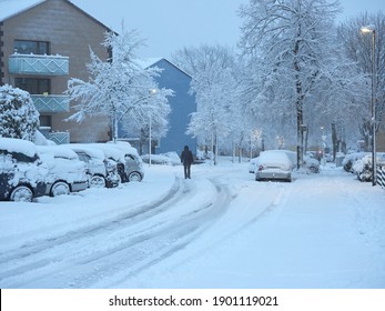 A man walking in the middle of the road during a snowstorm. Snow-covered pavements. Winter attack in Germany. Heavy snowfall in Heiligenhaus.