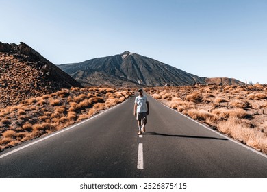 A man walking on a deserted road Tenerife with a volcanic Teide mountain  - Powered by Shutterstock