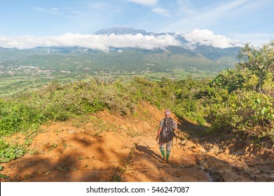 A Man Walking On Dirt Hiking Track Overlooking Valley With Mount Kinabalu At Far Background In Sabah Malaysian Borneo.