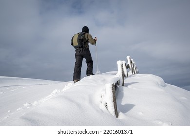 A Man Walking On The Fresh Snow, Moody Sky Overhead.