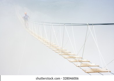 Man Walking On Hanging Bridge In Fog.