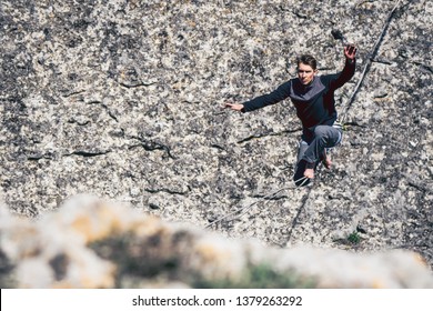 Man walking on high line and attempt to stand up and make step above mountains. High line contest. - Powered by Shutterstock