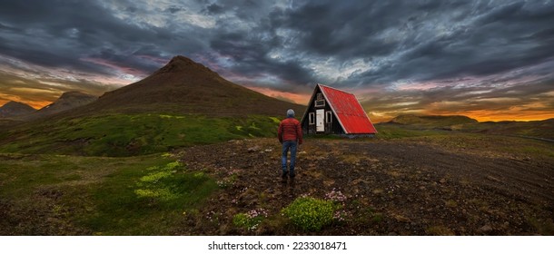 Man walking on the mountain with cabin in the background - Powered by Shutterstock