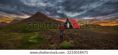 Man walking on the mountain with cabin in the background