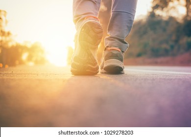 Man Walking On Road With Sun Light Flare ,close Up On Shoe Jogging Workout Wellness After Work