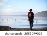 Man walking on the rocks. Unrecognizable people playing on Muriwai Beach in summer. Auckland. 