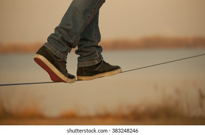 man walking on Slackline on the background of the river. Visible only  legs