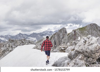 Man Walking On The Snow In Shorts On Top Of An Alpine Mountain In Tyrol