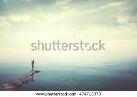 Man walking on stones finding balance over water 