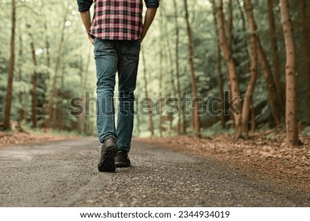 Man walking on sunlit trail in autumn forest enjoying peaceful walk in nature 
