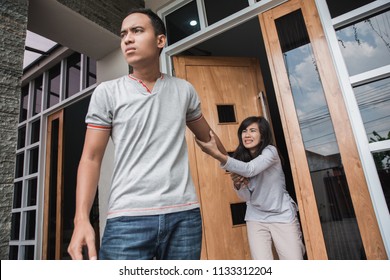 Man Walking Out Of Door During Argument With His Wife Indoors