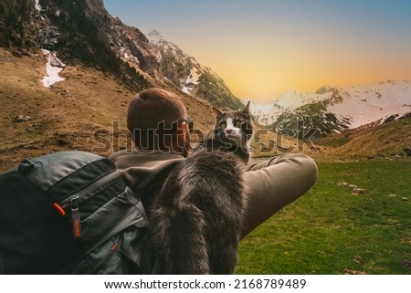 Man walking outdoors in mountains with his cat friend on the shoulder. Scene in nature at sunset. Man spending time with his pet. Best life moments 