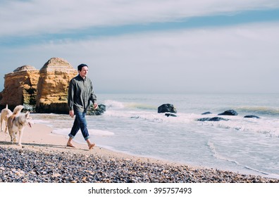 Man Walking With Siberian Husky And Labrador Dog On Beach