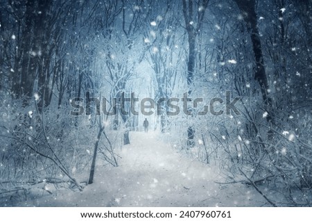 man walking through blizzard in winter forest